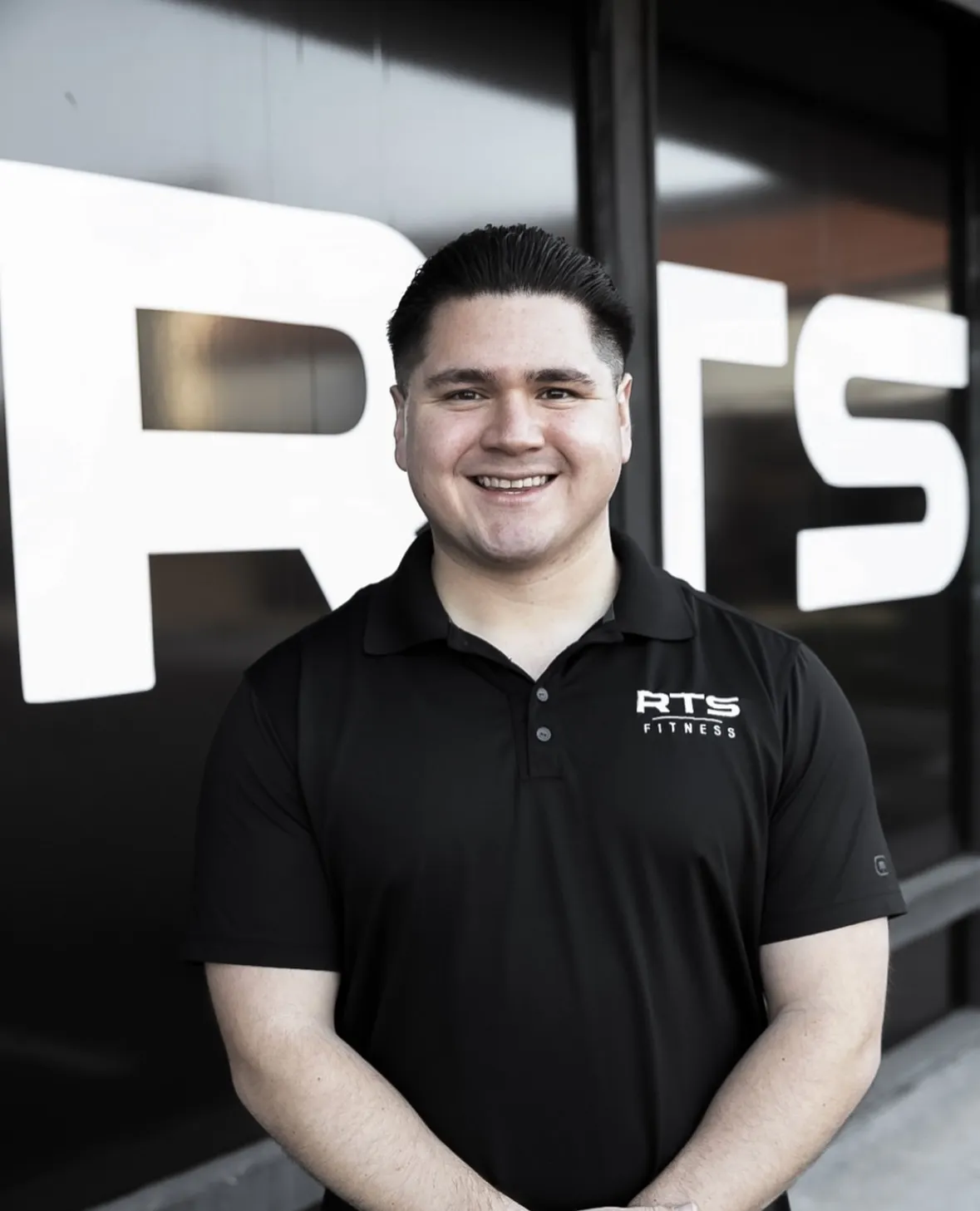 Coach Ray of RTS Fitness standing in front of the gym's RTS window lettering.